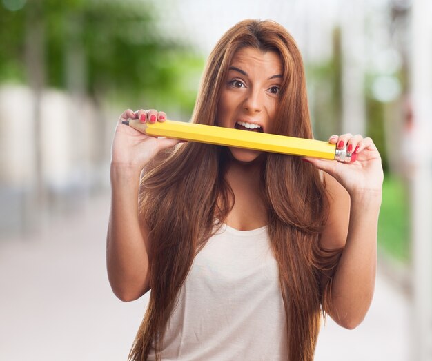 Young beauty eating yellow pencil. 