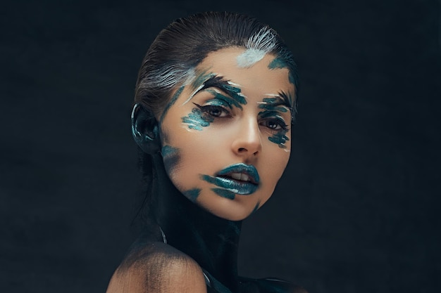 創造的なメイクの若い美女。彼女の顔に青と黒の影が描かれています。概念的なアイデア。