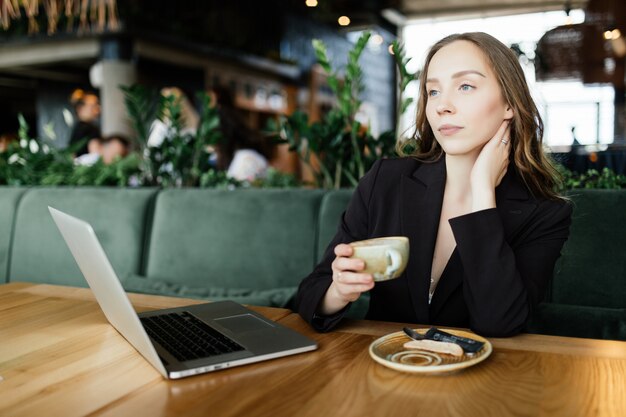 Young beauty woman working at laptop in coffee shop