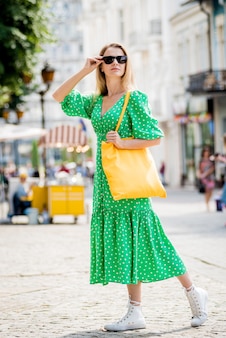 街​の​背景​に​黄色​の​リネンエコバッグ​を​持つ​若い​美しい​女性