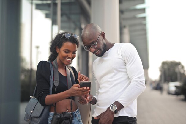 거리에서 스마트폰을 들고 있는 젊은 흑인 부부