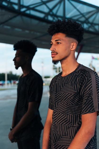 Free photo young black male standing on mirrored background