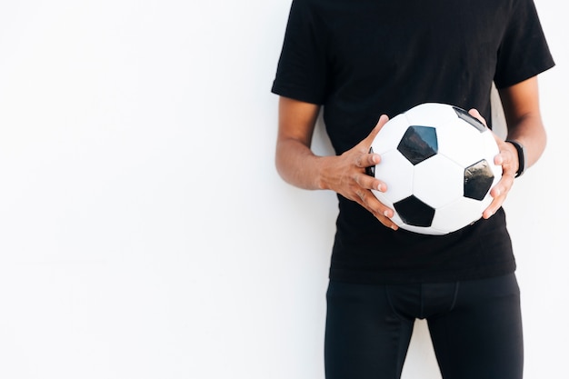 Молодой черный человек в черном с футбольным мячом