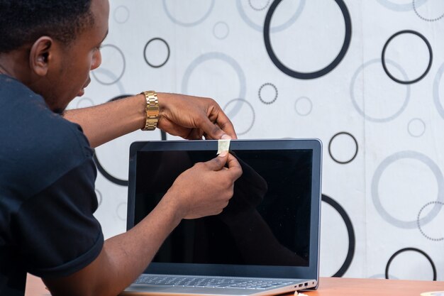 Young black man taping his laptop's webcam