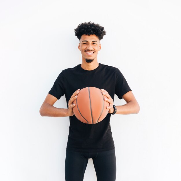 Молодой черный человек с баскетболом, глядя на камеру