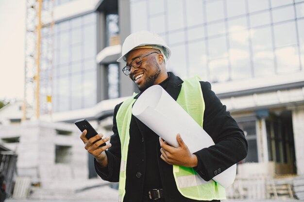 Young black race man with blueprint stading near glass building