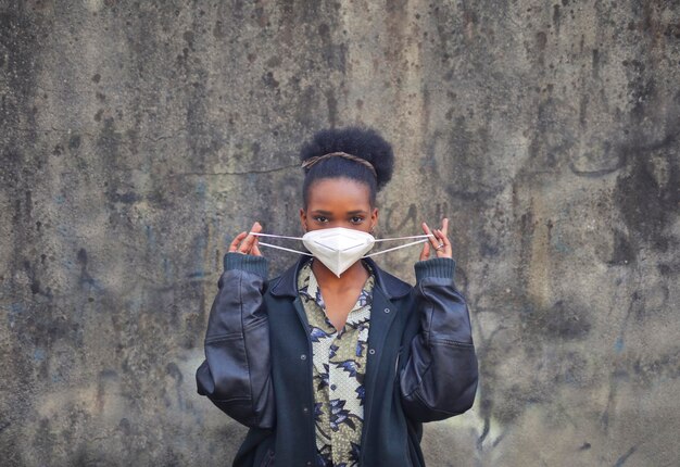 молодая черная женщина надевает защитную маску