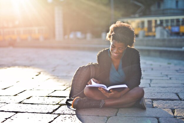 通りの若い黒人女性が本を読む