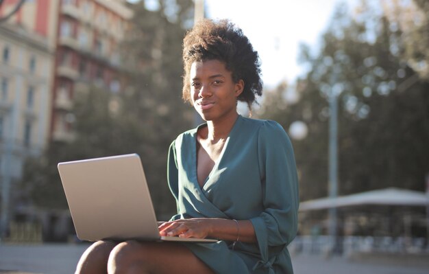 молодая черная женщина на улице с компьютером