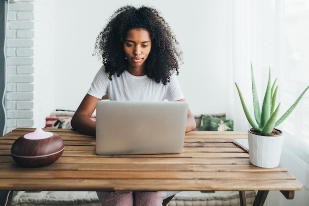 Free photo young black woman using laptop at home