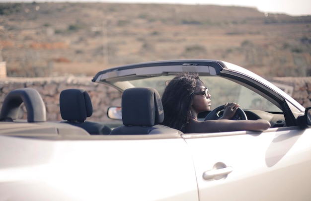 young black woman behind the wheel of a convertible car