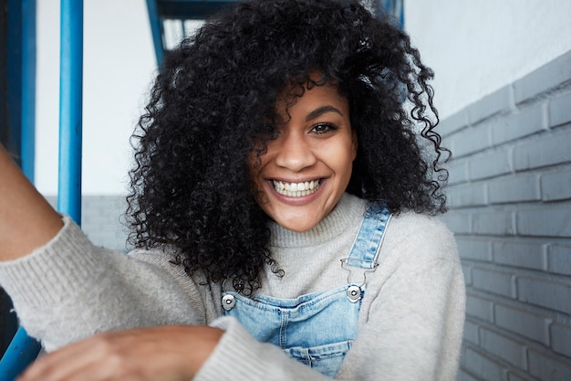 Free photo young black woman with afro hair laughing and enjoying