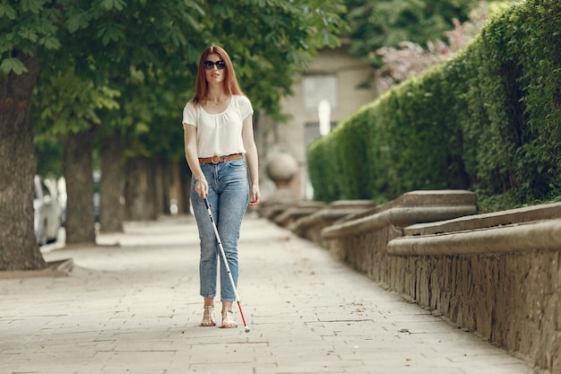 Foto gratuita giovane cieco con bastone lungo che cammina in una città