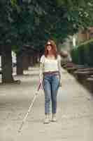 Free photo young blind person with long cane walking in a city