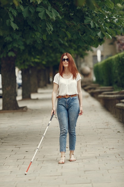 Young blind person with long cane walking in a city