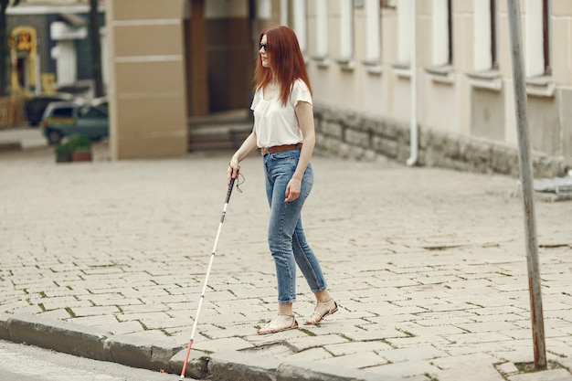 Young blind person with long cane walking in a city