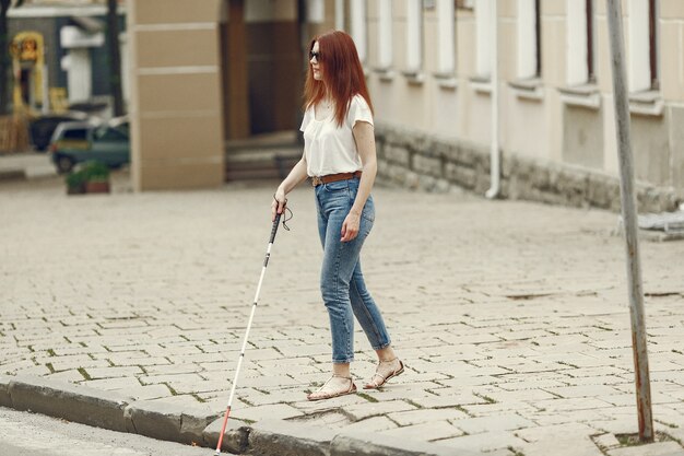 Young blind person with long cane walking in a city