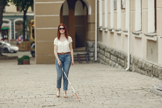 Young blind person with long cane walking in a city