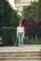 Foto gratuita giovane cieco con bastone lungo che cammina in una città