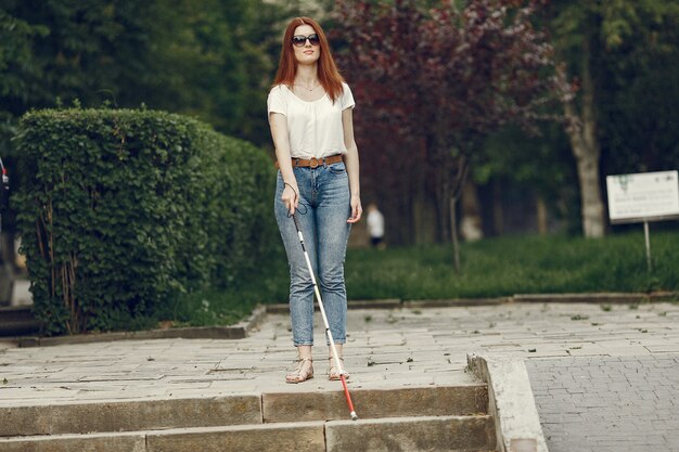 Young blind person with long cane walking in a city