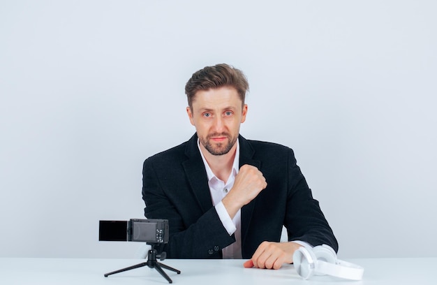 Young blogger man is posing to camera by raising up his fist on white background