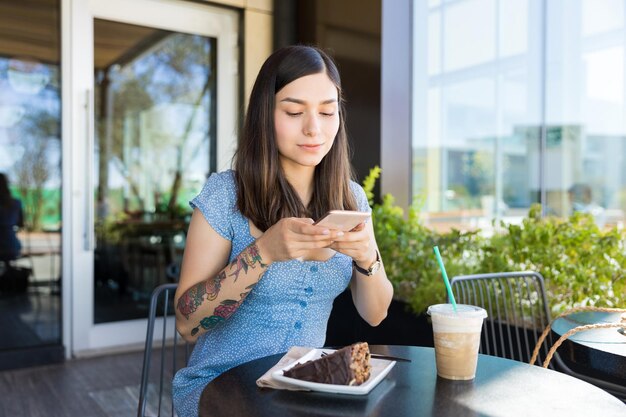 ショッピングモールでスマートフォンを介してペストリーを撮影する若いブロガー