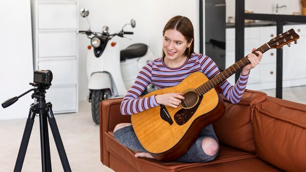 Young blogger recording herself playing the guitar