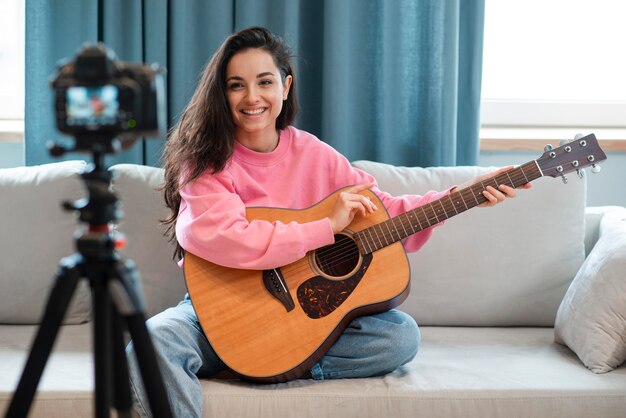 Young blogger recording herself showing how to play the guitar