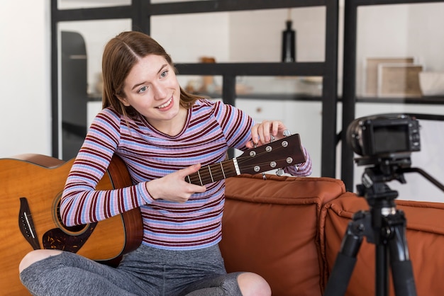 Young blogger recording herself and tuning her guitar