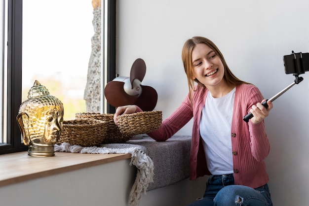 Free photo young blogger recording herself next to window showing home decor