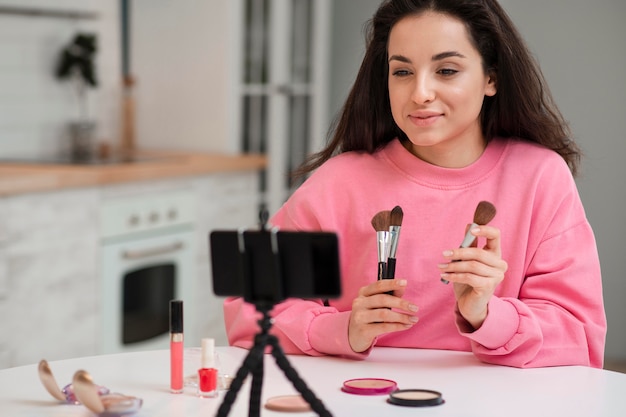 Young blogger recording video with make-up accessories