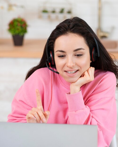 Young blogger with headset looking at laptop and pointing up