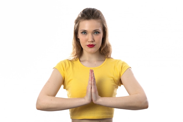 Giovane donna bionda con pregare giallo della maglietta