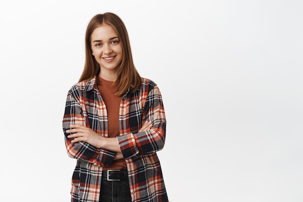 Young blond wonan in plaid shirt, cross arms on chest and smiling with confidence standing over white background.