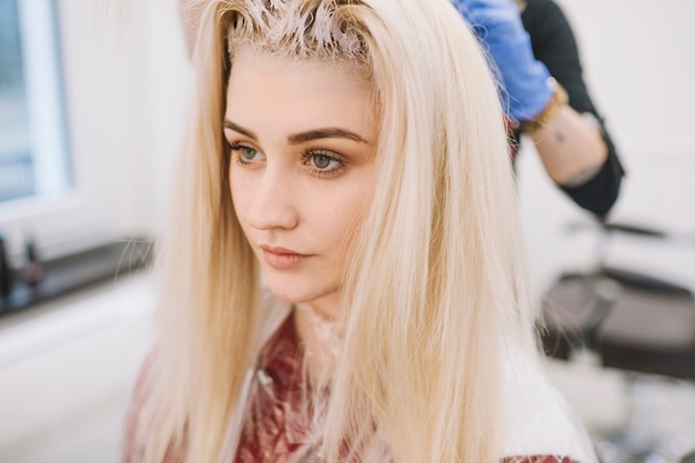 Young blonde in chair of hairdresser