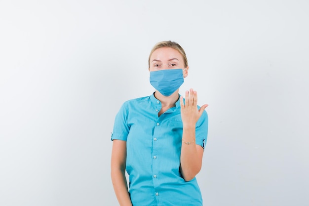 Young blonde female in casual clothes, mask showing nails and looking gloomy