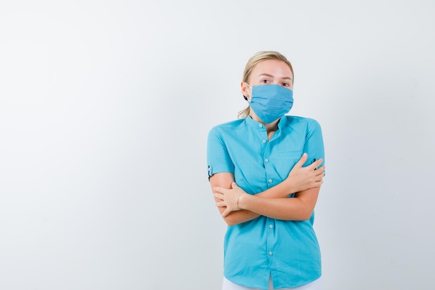 Young blonde female feeling cold in casual clothes, mask and looking unwell