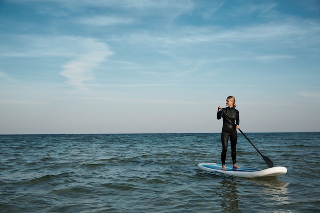 Молодая блондинка женщина на доске с веслом в море