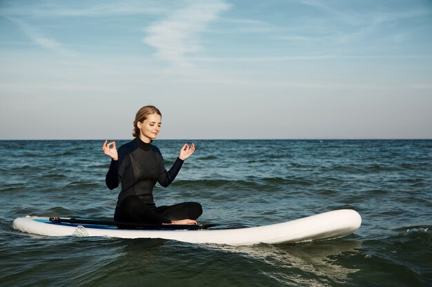 Young blonde female on paddleboard at sea