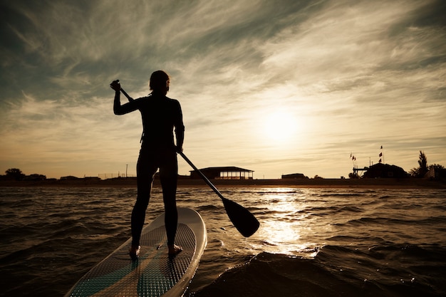 Young blonde female on paddleboard at sea