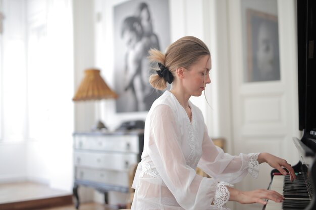 Young blonde female playing the piano during daytime