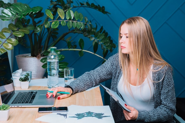 Young blonde female psychologist using laptop in clinic