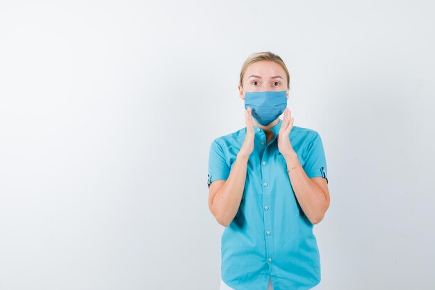 Young blonde female showing size sign in casual clothes, mask and looking confident