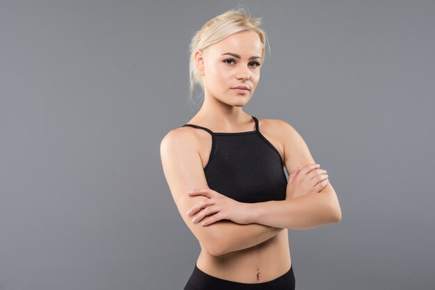 Young blonde fit sporty girl woman in black sportswear demostrate her strong muscular body stretching
