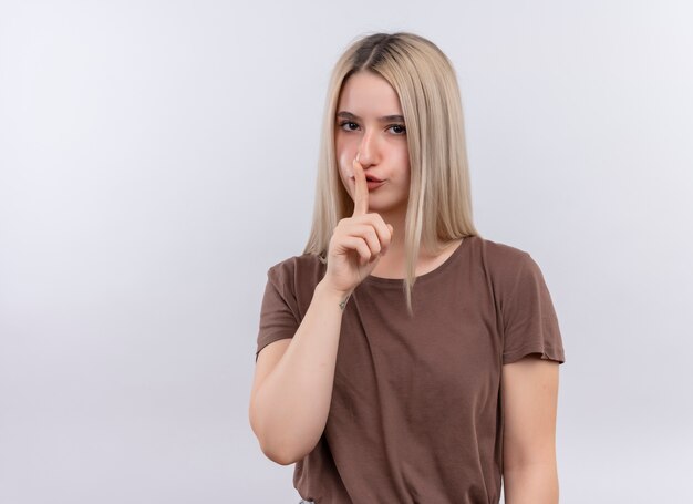 Young blonde girl gesturing silence on isolated white wall with copy space