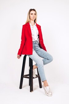 Молодая блондинка в красном пальто на белом