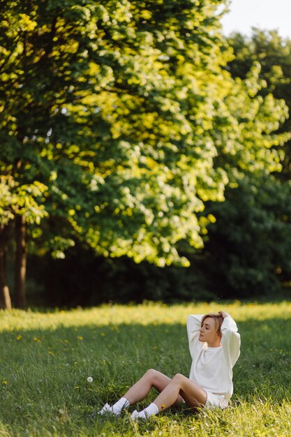 Young blonde girl is wearing a white hoodie smiling and walking in the woods