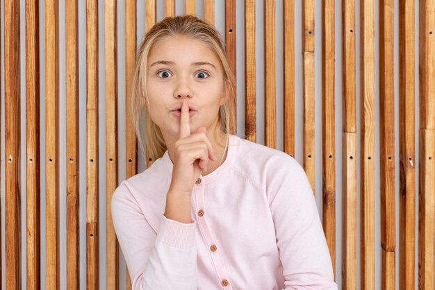 Young blonde girl making shh sign