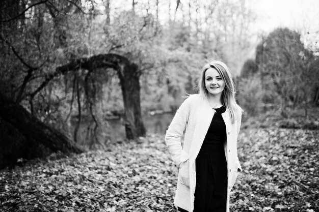 Young blonde girl at pink coat posed on autumn park