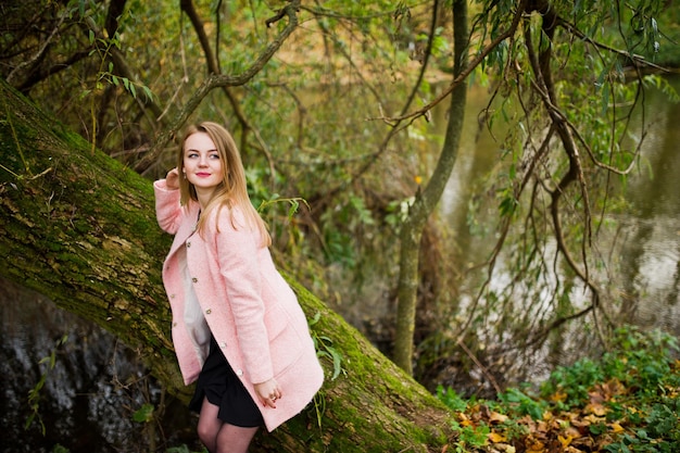 핑크 코트에 젊은 금발 소녀가 공원에 포즈